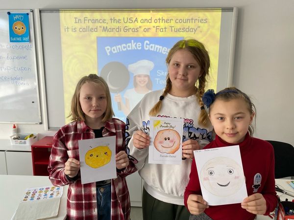 Дети держат в руках рисунки блинов на тематическом занятии "Масленица" занятии по английскому языку